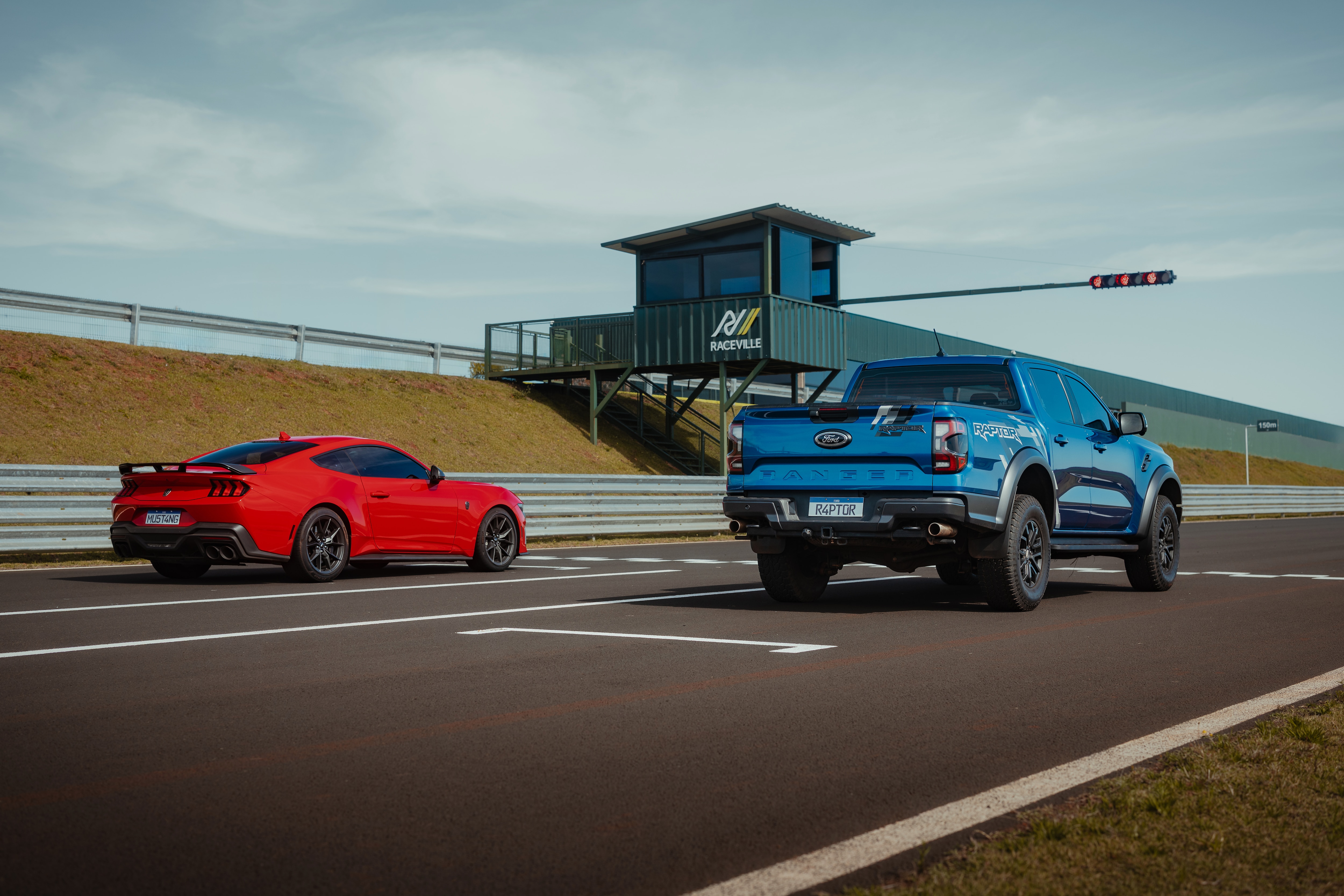 Ford Mustang Dark Horse vermelho na pista com uma Ford Ranger Raptor azul